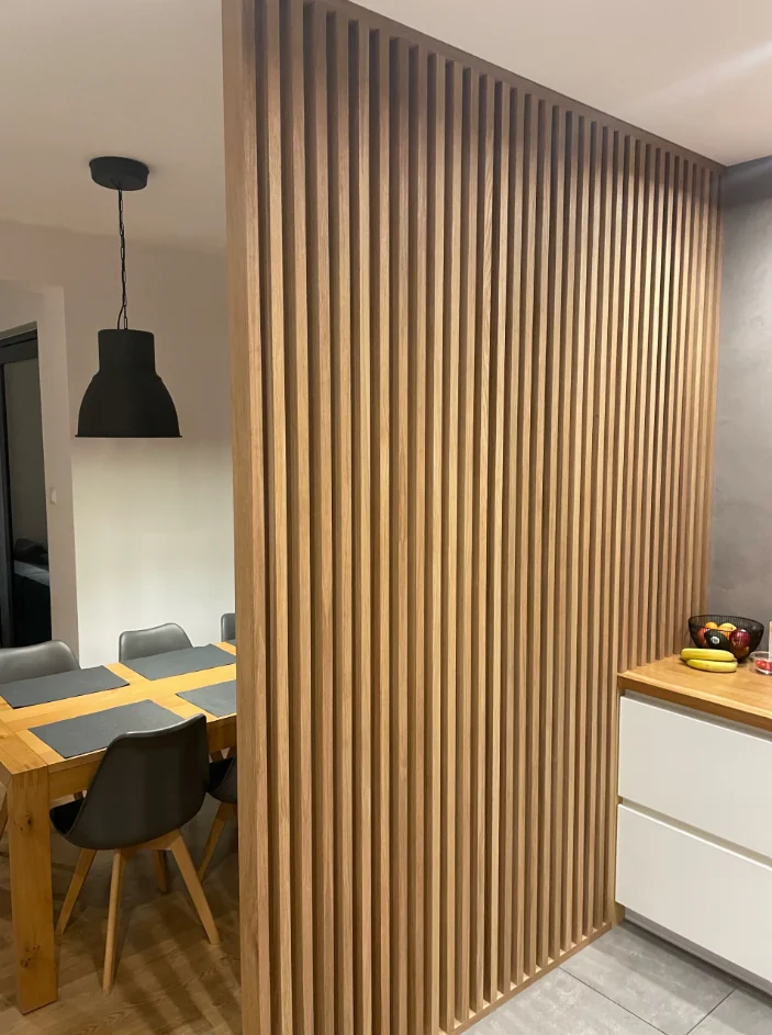 Floor-to-ceiling timber veneer slatted room divider with framing, shown as a manufacturer reference